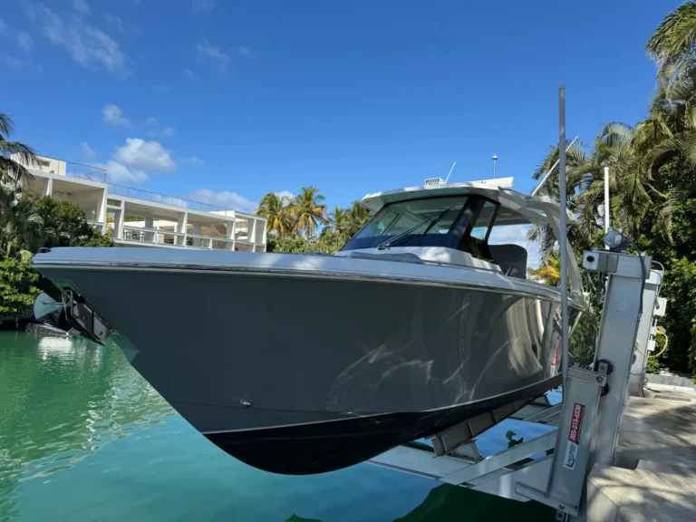 Grey gelcoat hull on a boat lift in Miami reflecting palm trees after a wax